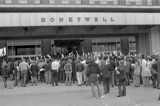 Protesters gathered outside a building with a Honeywell sign.