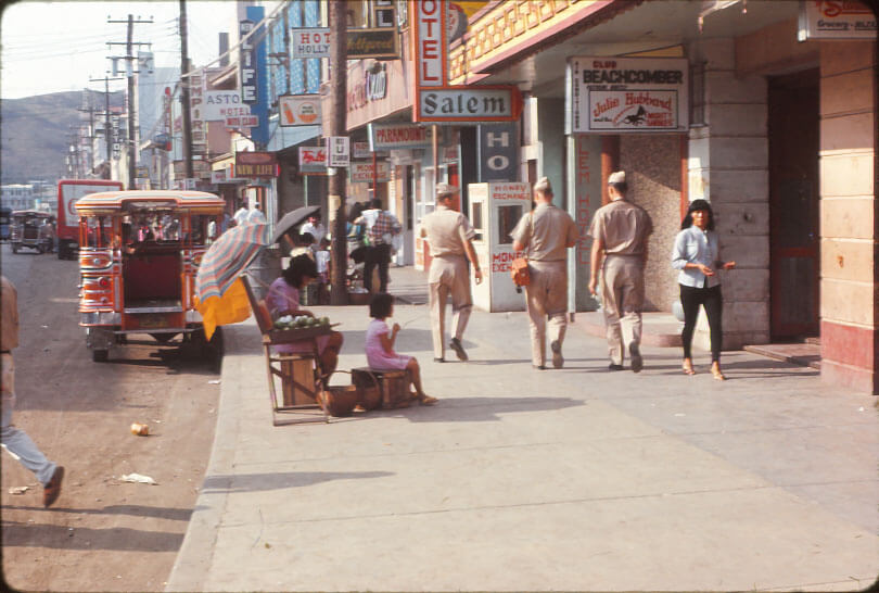 A street scene in an Asian city, three men in beige, probably U.S. Marines or Navy personnel, who are off duty.