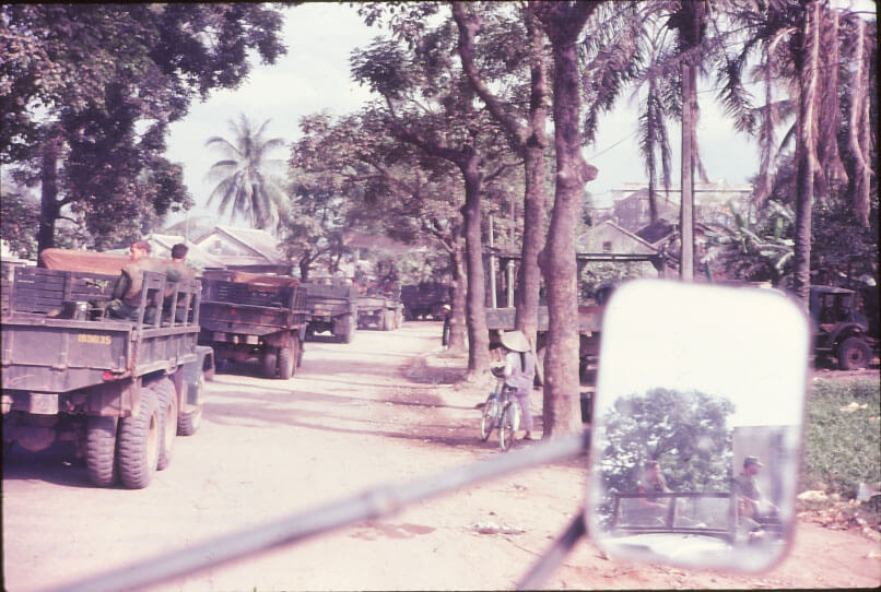 Taken from a truck: a convoy with a mirror that has the images of Marines sitting on the back of the truck.