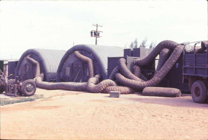 Exteriors of a row of arched structures with large ducts pumping air into them.