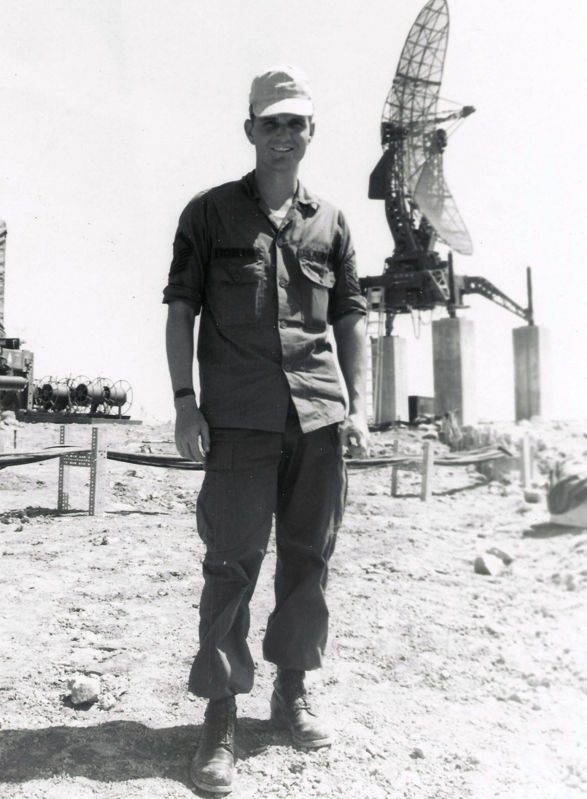 A U.S. soldier standing outside, in front of what looks to be a large satellite dish.