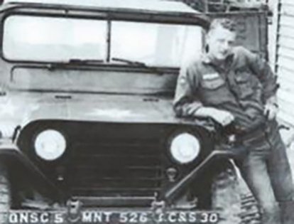 A young soldier leaning on a Jeep. Image from vvmf.org/Wall-of-Faces.