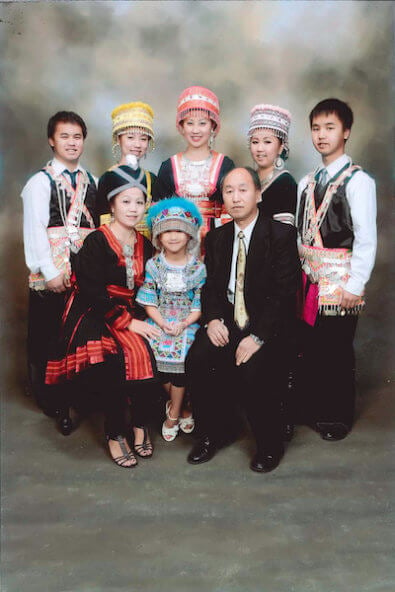 Portrait of a family of 8 in traditional Hmong costume.