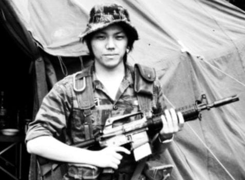 Young Asian soldier wearing a boonie hat and holding a rifle.