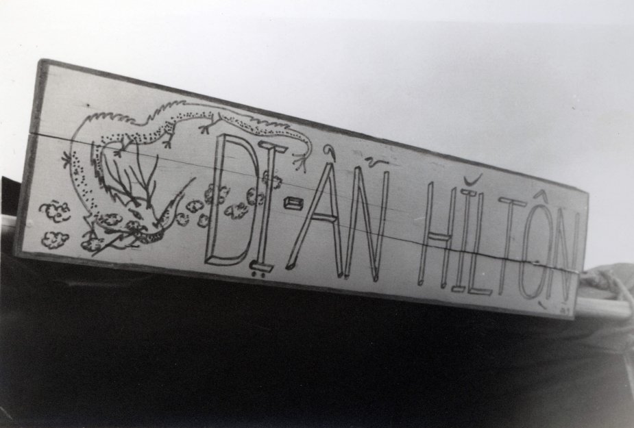 A building sign with an illustrated lizard or dragon; text says "DI-AN HILTON".