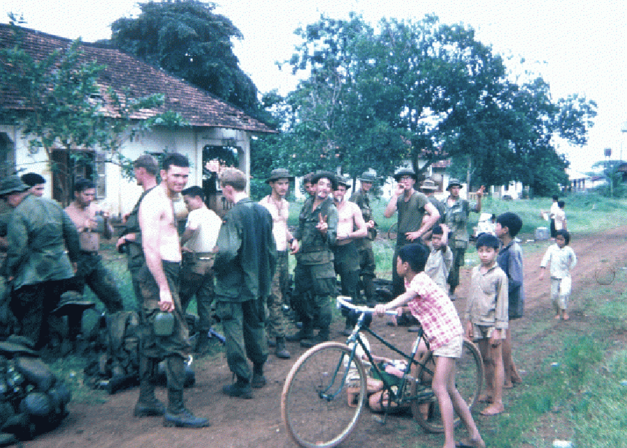 A group of U.S. soldiers and young Asian children with bicycles.