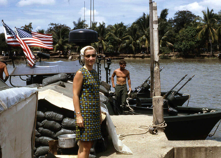 Young woman posing for a photo on a River Patrol Boat with American flags flying