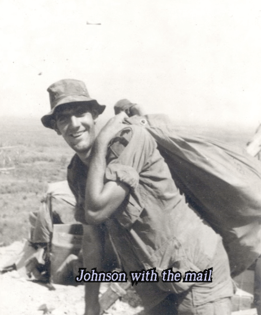 A happy young man in uniform and a boonie hat with a mail bag thrown over his shoulder. Text on photo says "Johnson with the mail."