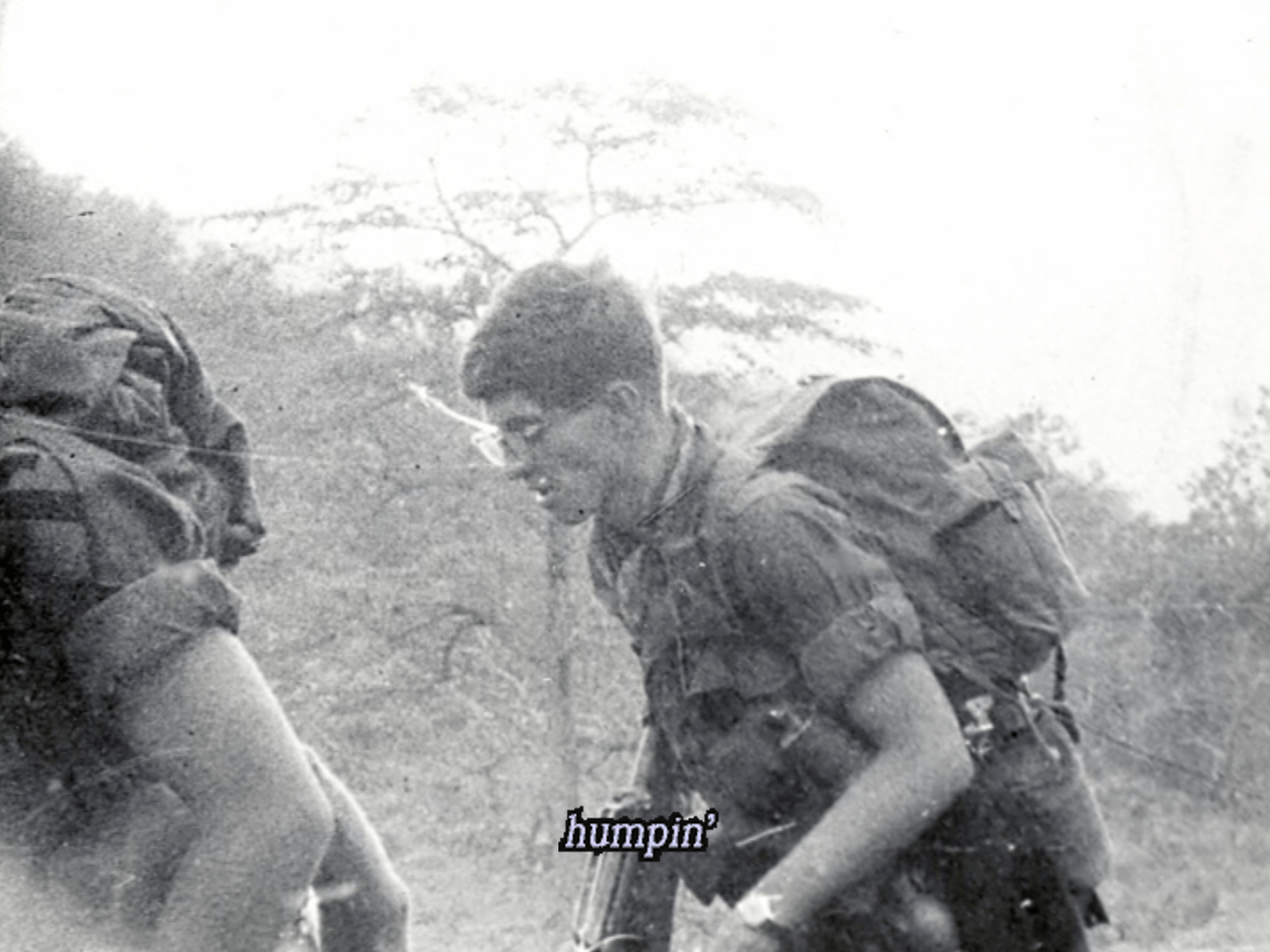 Two soldiers with large packs on their backs, walking. Text on photo says "humpin'."