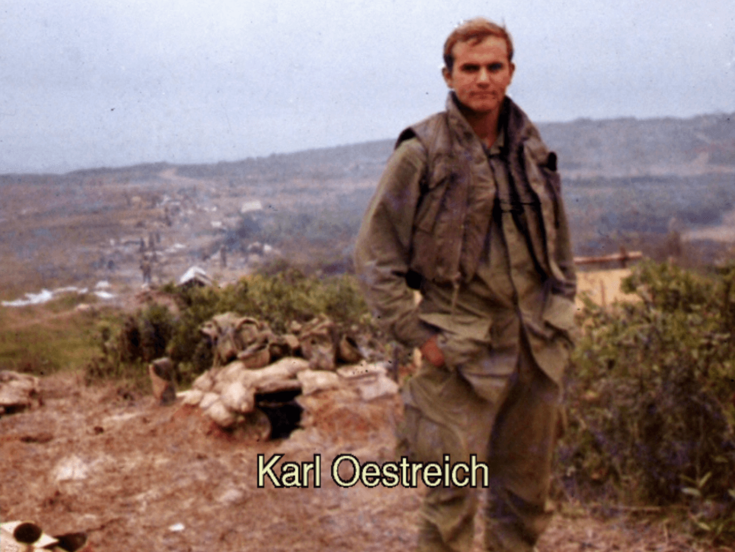 A soldier standing on an overlook with his hands in his pockets. Text on photo says "Karl Oestreich."