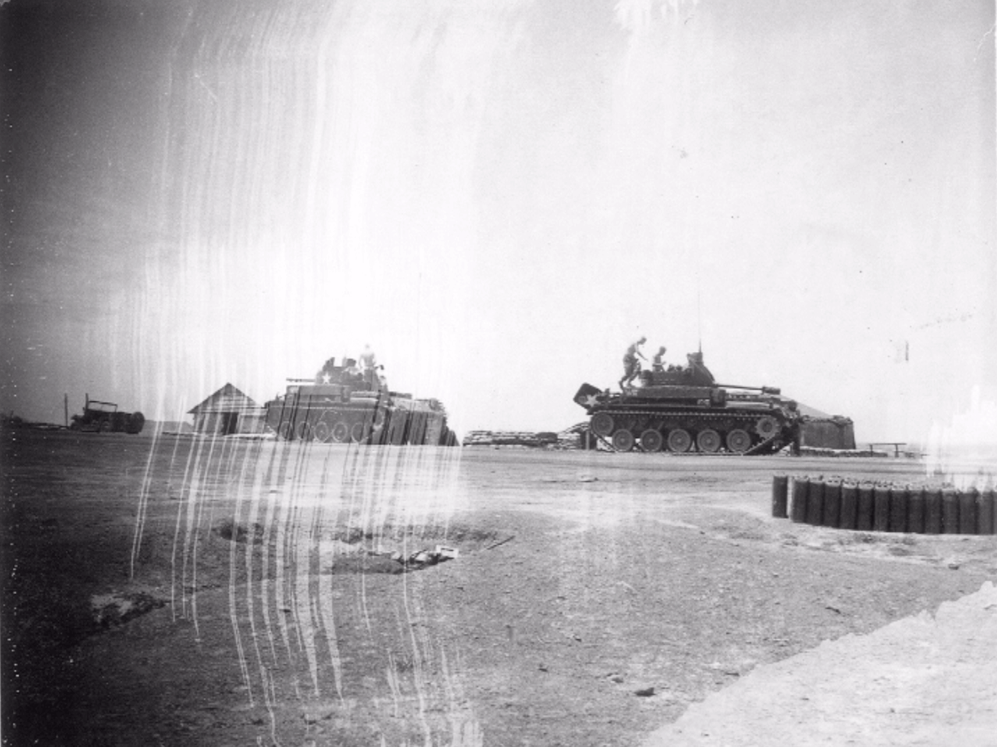 Two tanks moving across a desolate landscape.