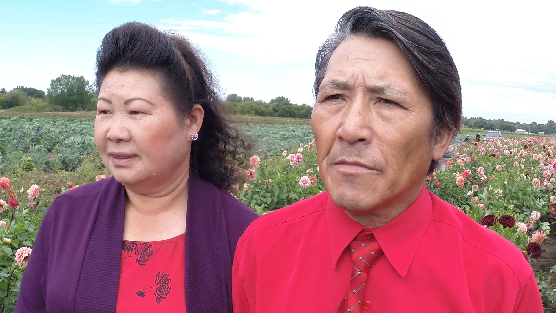 An Asian woman and Asian man, standing in a field of flowers.