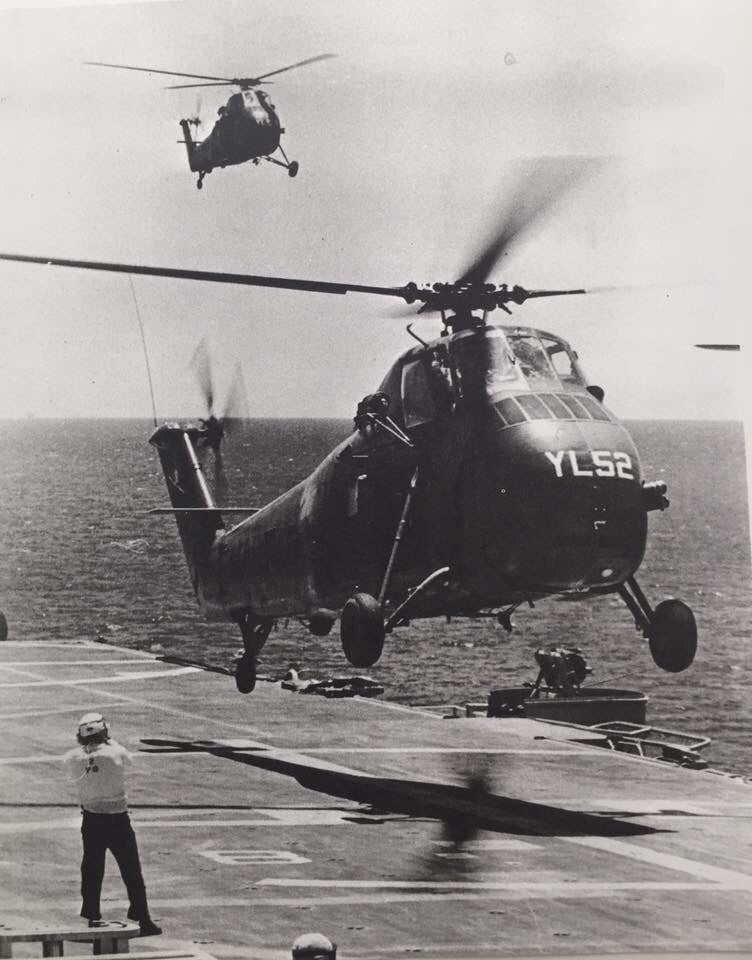 Two helicopters either taking off or landing on a large deck.