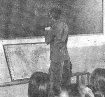 An Asian student writes at a blackboard.
