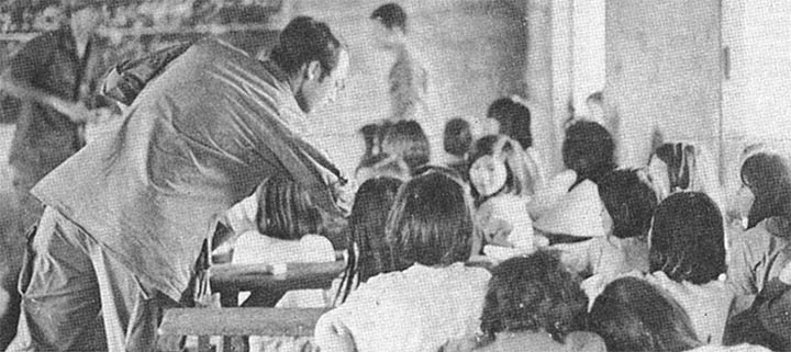 A US soldier handing out gifts to a classroom of young Asian children.