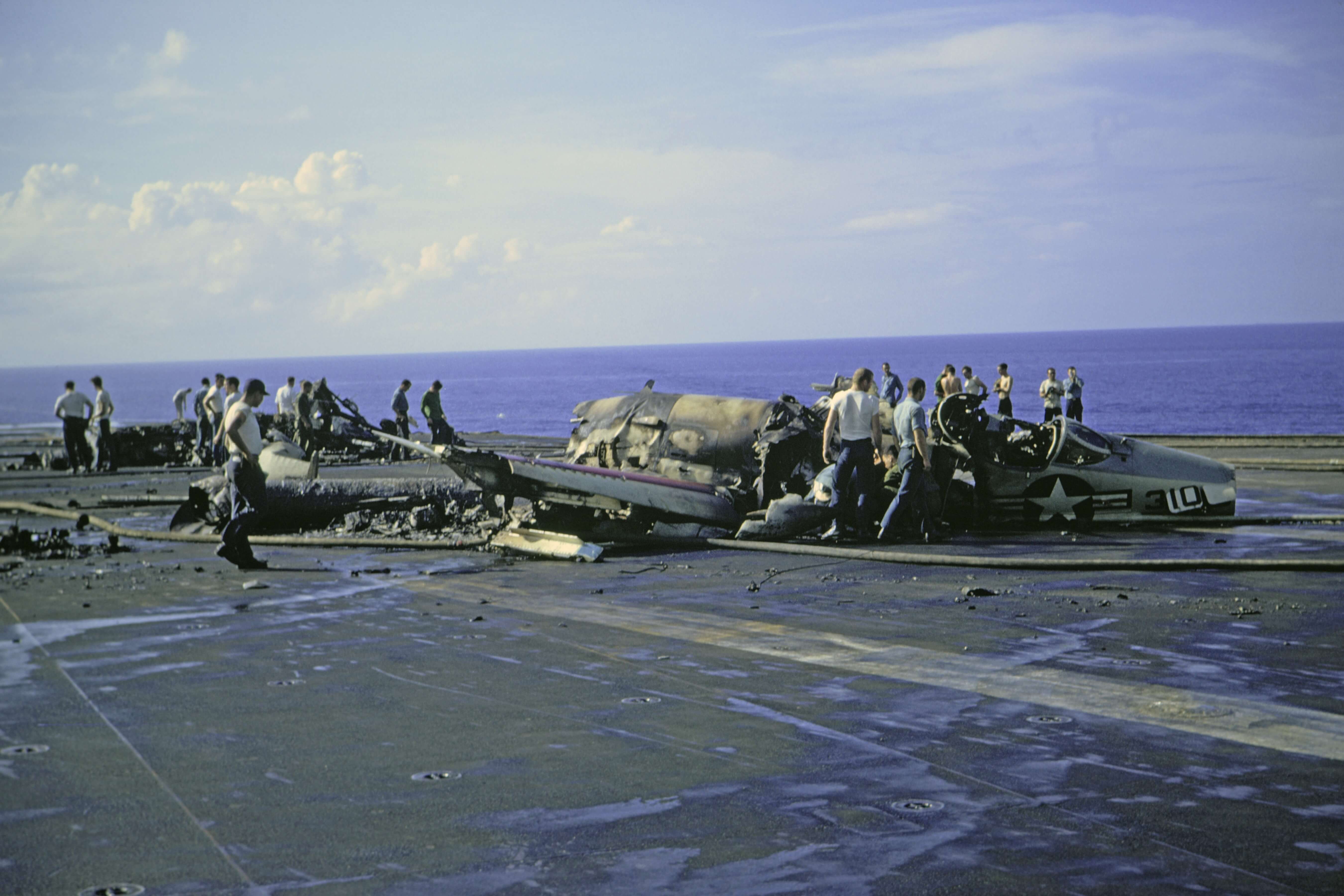 Plane wreckage on top of the deck of a large Navy boat.