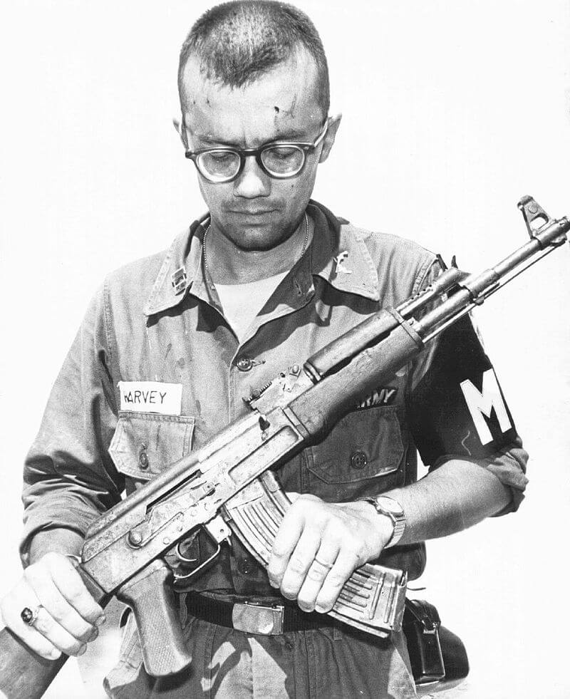 Photo of a military police officer holding and inspecting an AK-47.