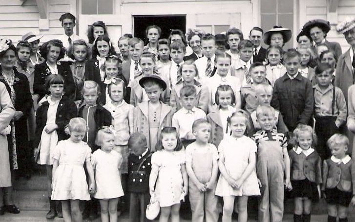 A class photo of students in Sunday clothes, ranging in age from toddler to high schooler, along with adult teachers, presumably.