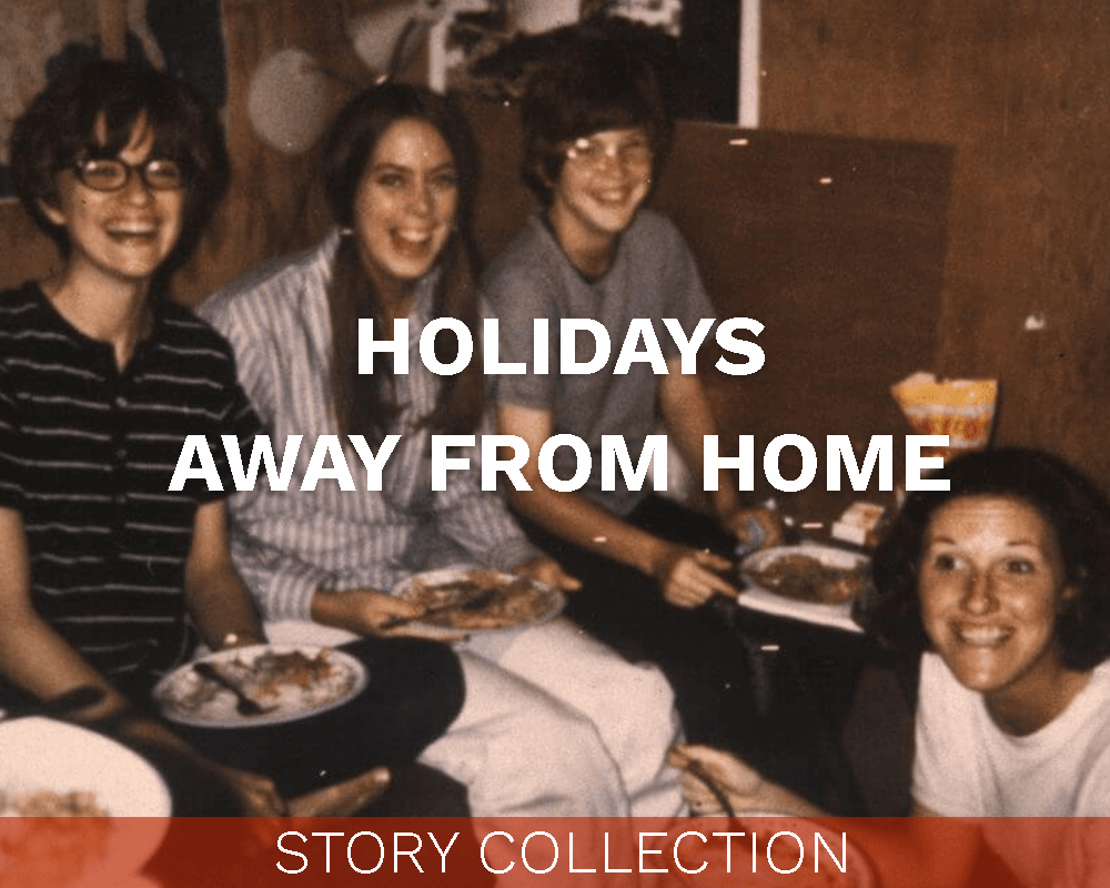Four cheerful looking women eating dinner in a hootch, with "Holidays Away From Home" text over the image.