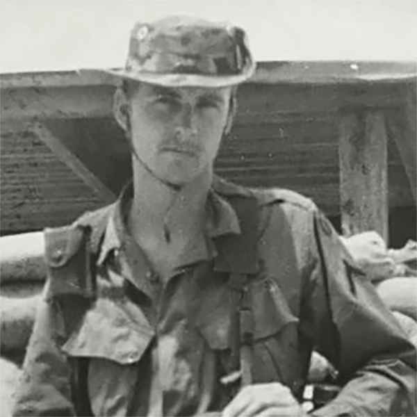 A soldier in a boonie hat looking right into the camera.