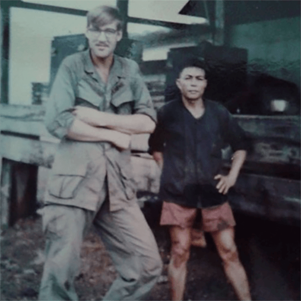 A very tall US soldier posing alongside a very small Asian man.