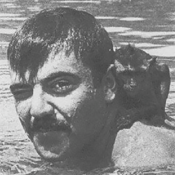 Close up of a mustachioed man swimming with a monkey clinging to his neck.