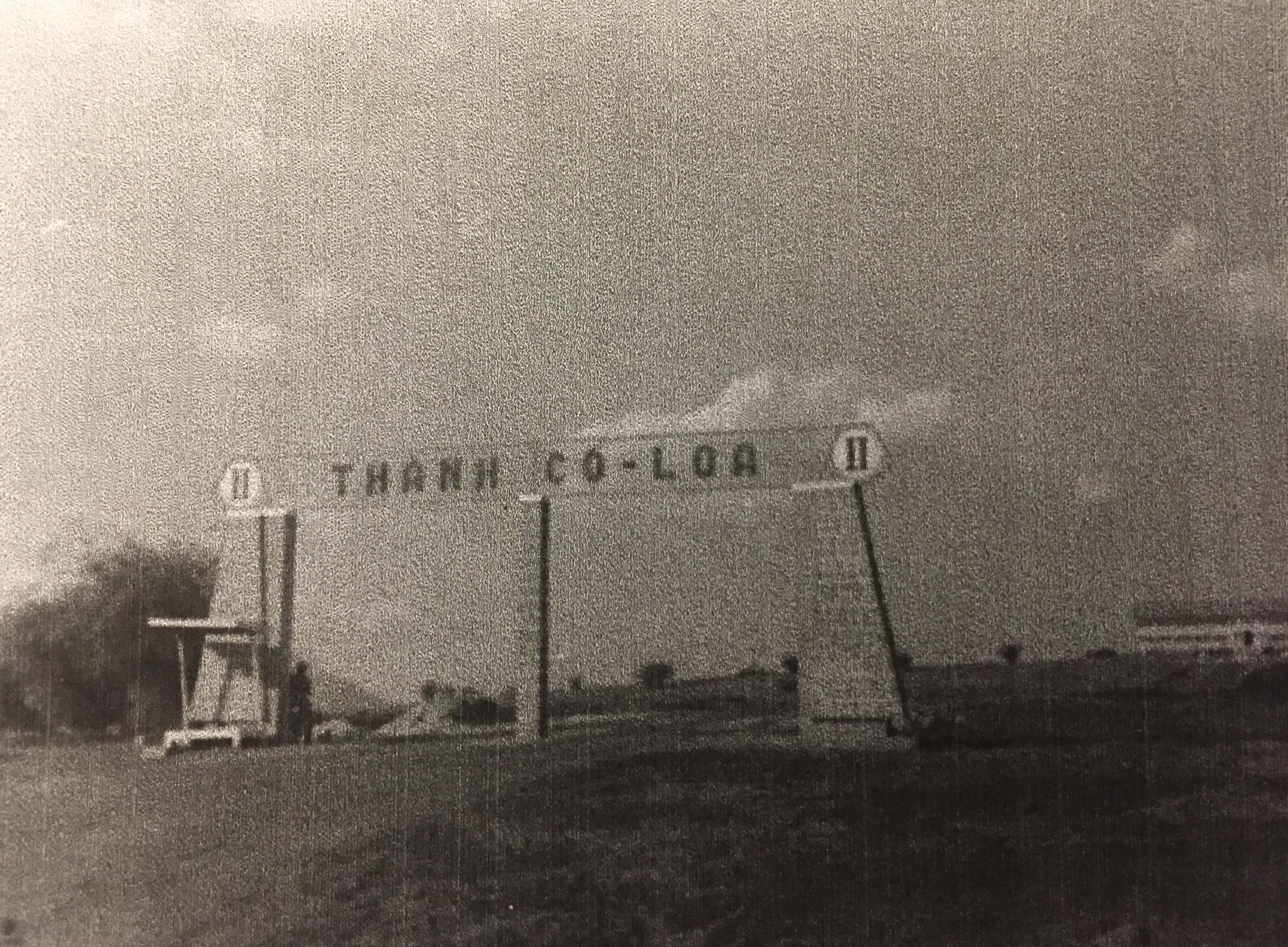 A large sign straddling a roadway, reads: "THANH CO-LOA".
