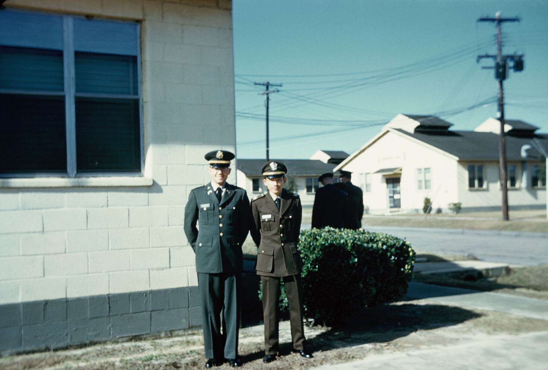 Two men in uniform standing side by side, one Asian and one American.