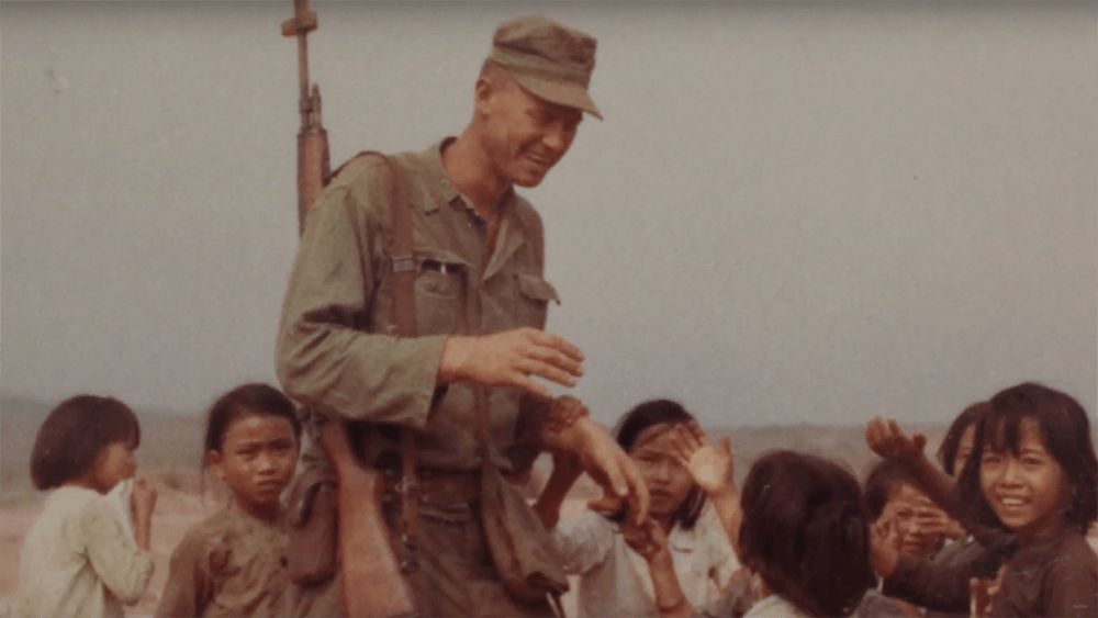 A smiling soldier surrounded by young Vietnamese children.