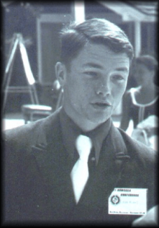 A young man in a suit and tie with an indiscernible name tag on.