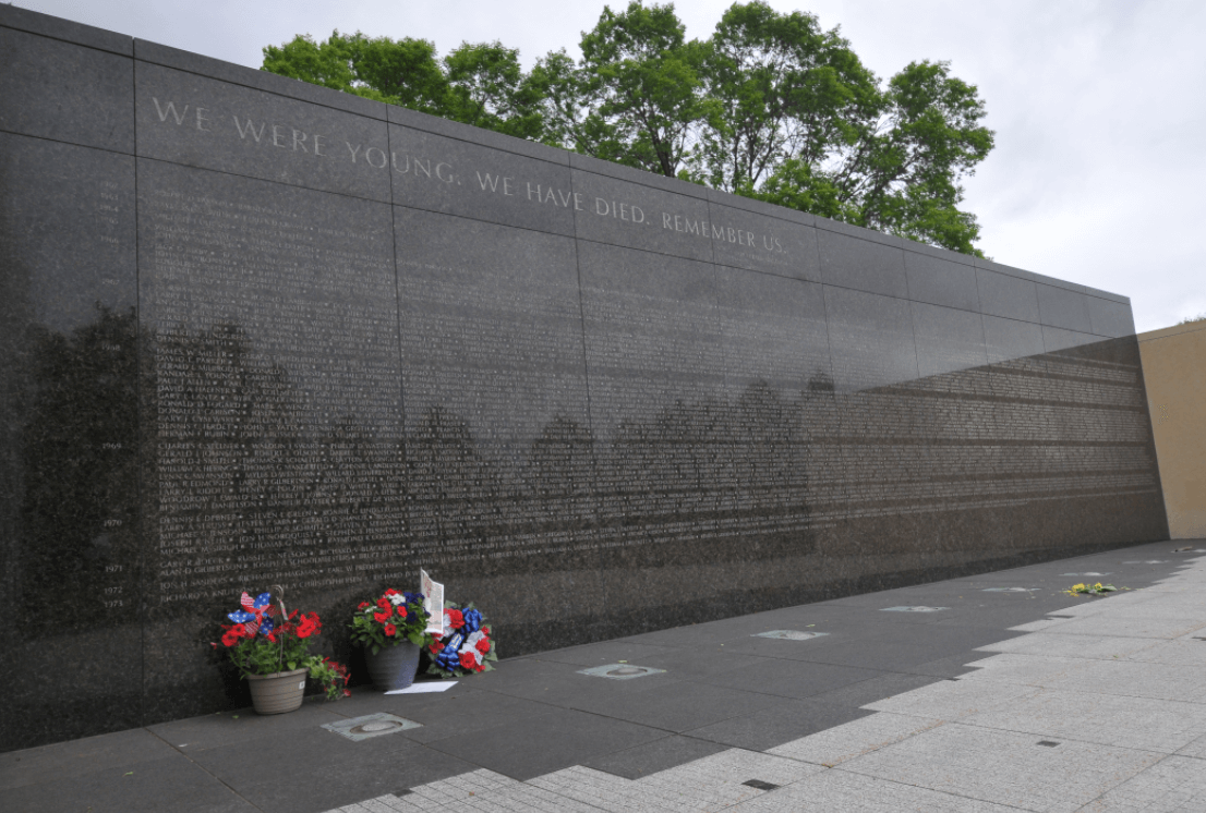 Vietnam Memorial on a cloudy day, two bouqets leaned up against the wall.