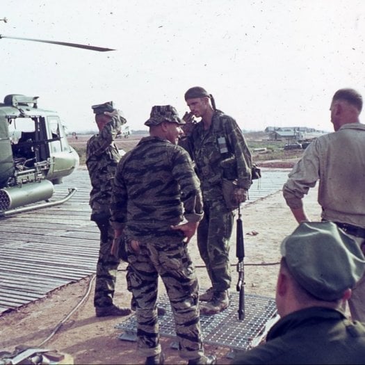 A group of five men in uniform, talking.