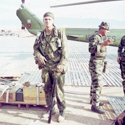 A U.S. soldier in full gear, standing next to a pallet of supplies.