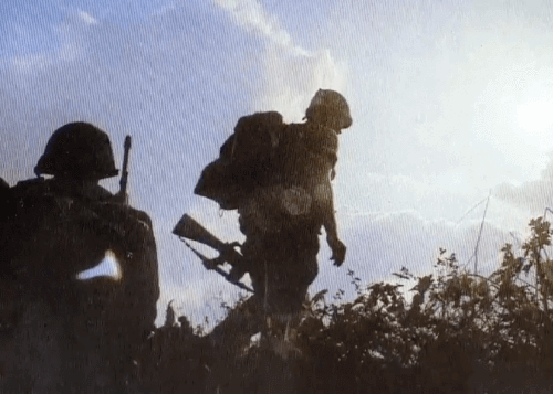 Two silhouetted soldiers against a sunny sky.