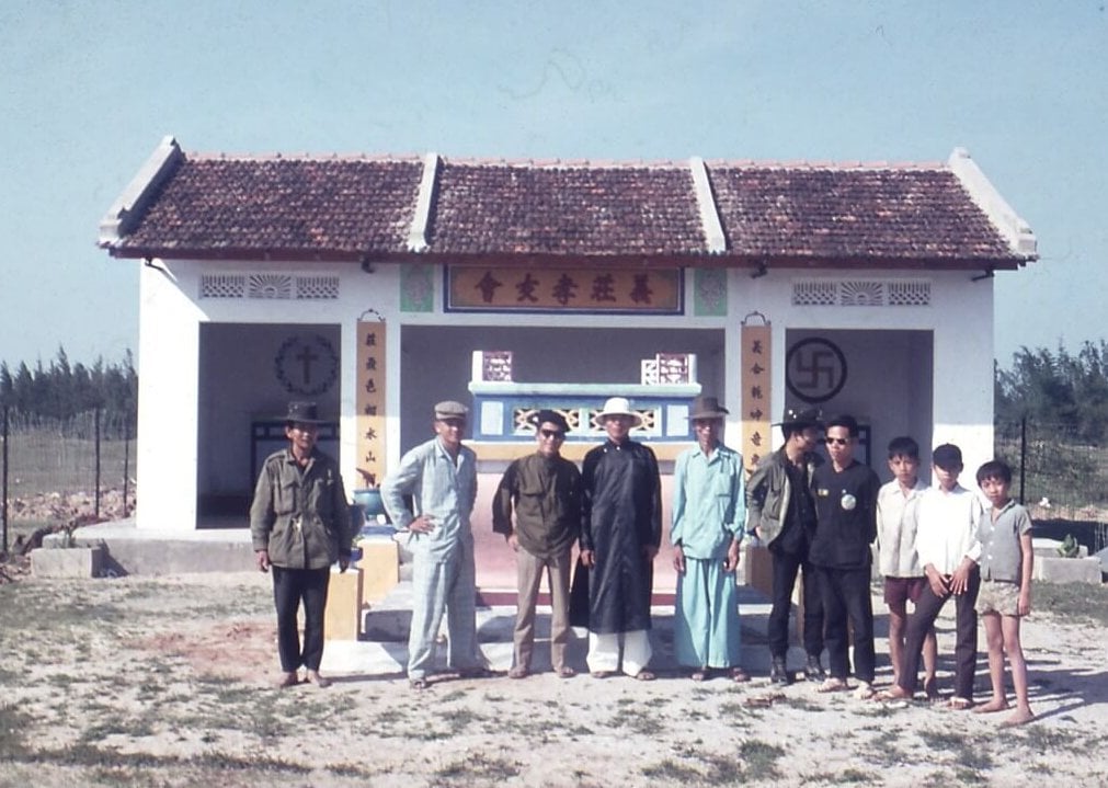 A group of Asian men and boys standing in front of a mausoleum.