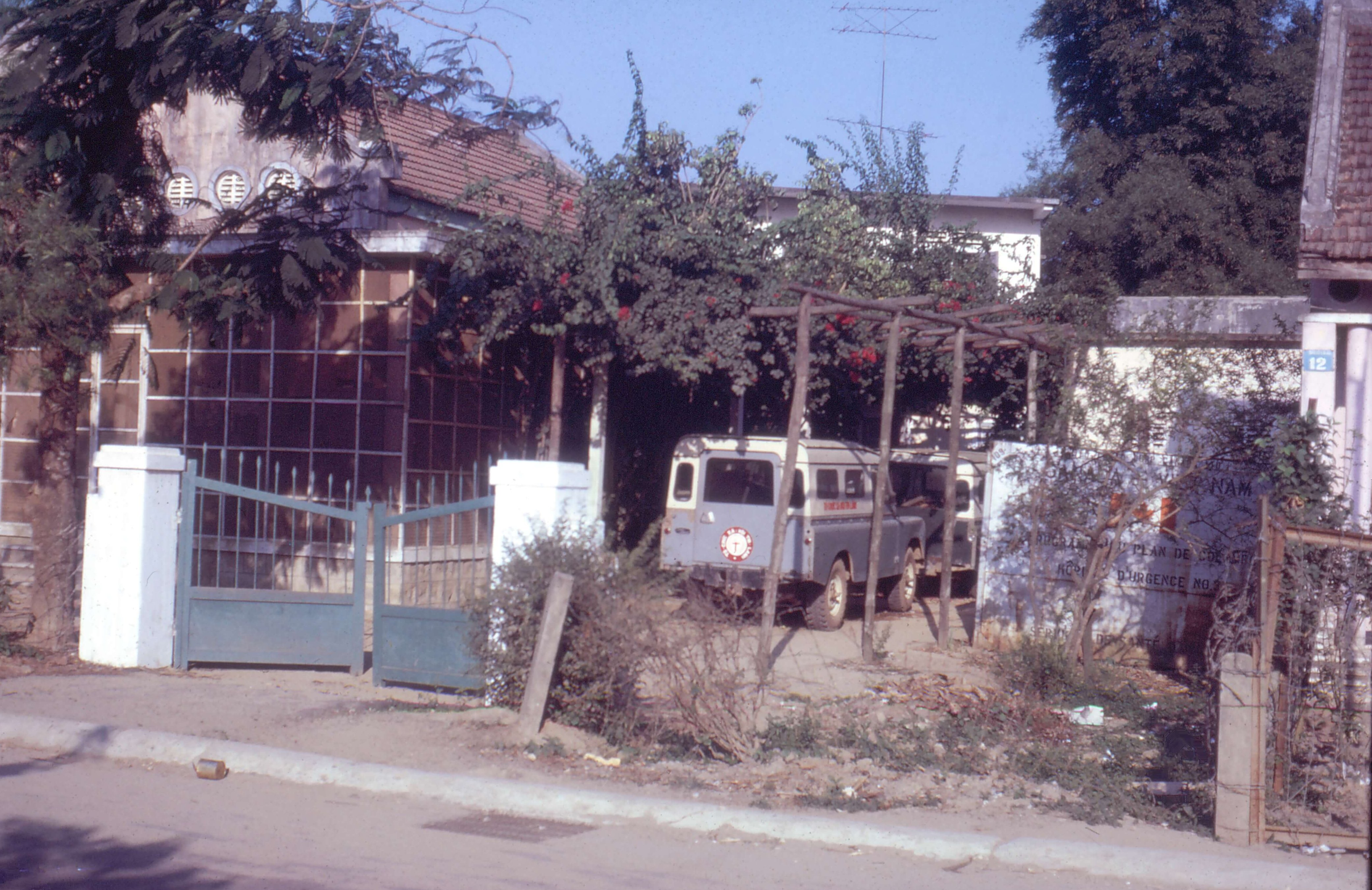 Exterior of an Asian house and its adjacent pergola, with cars parked beneath.