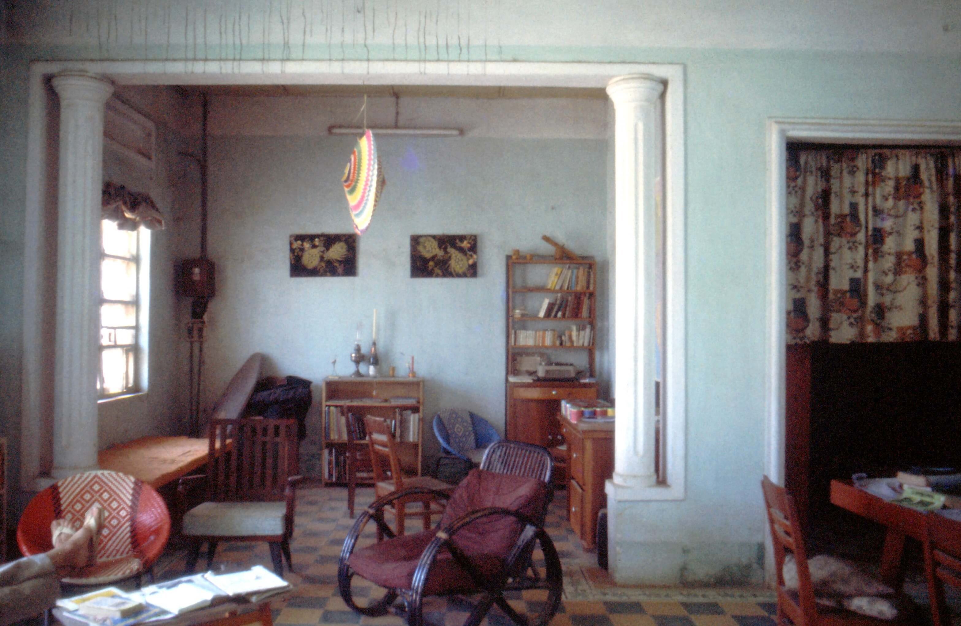 Living room of a house with a lot of natural light. Two crossed feet in flip-flops are poking out in the lower left corner.