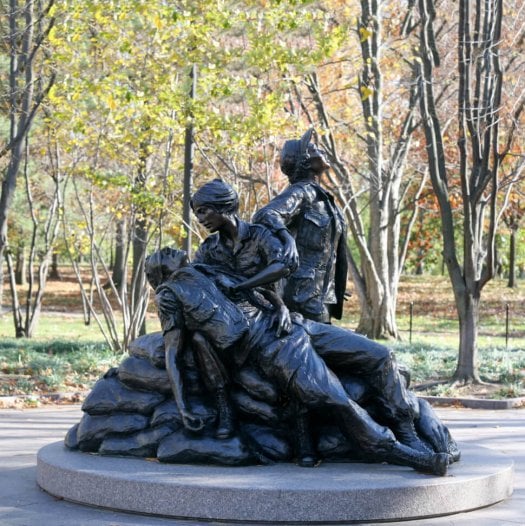 A bronze statue of three nurses helping a wounded soldier.