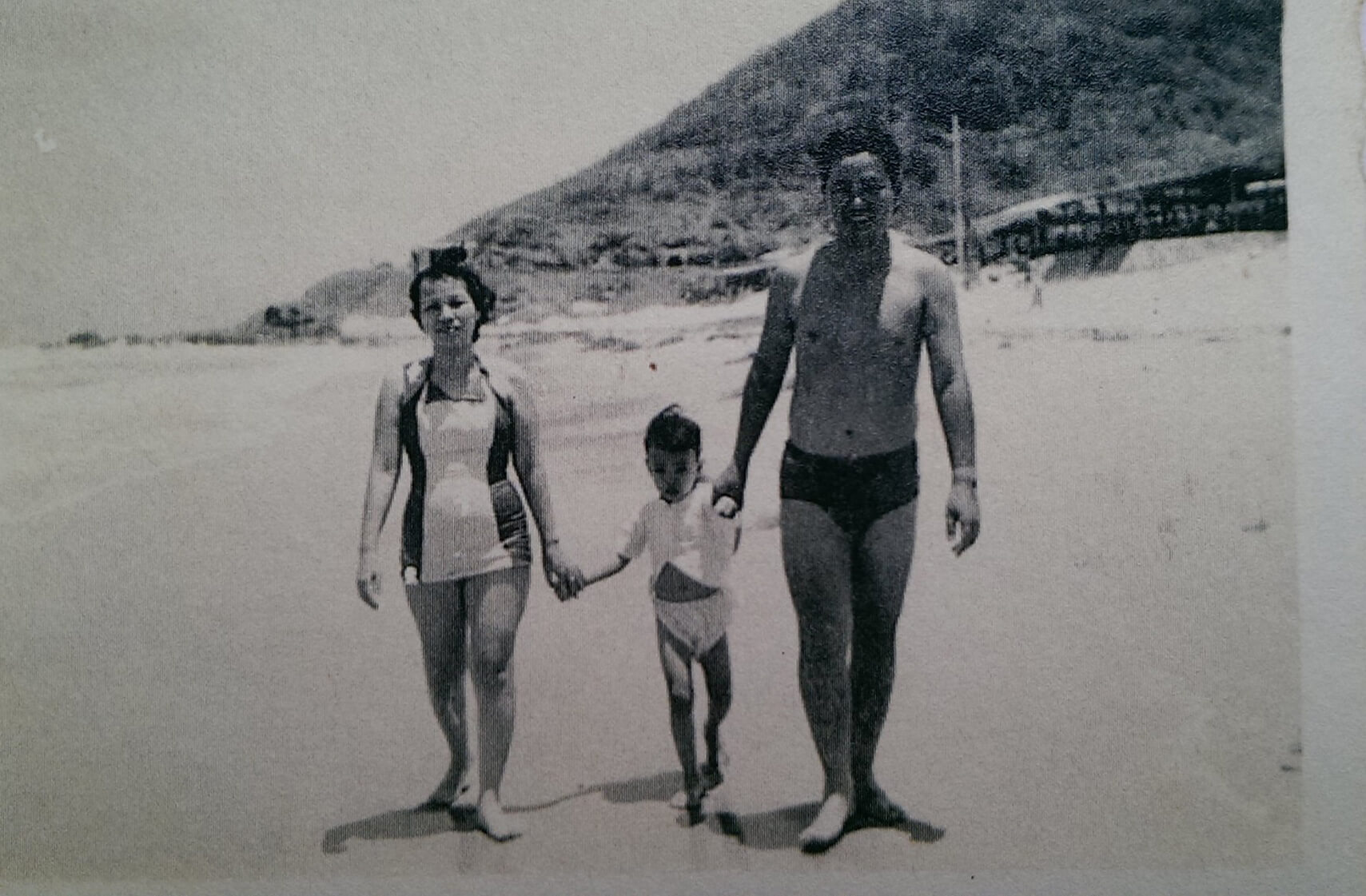 Black and white photo of three Vietnamese people walking on a beach.