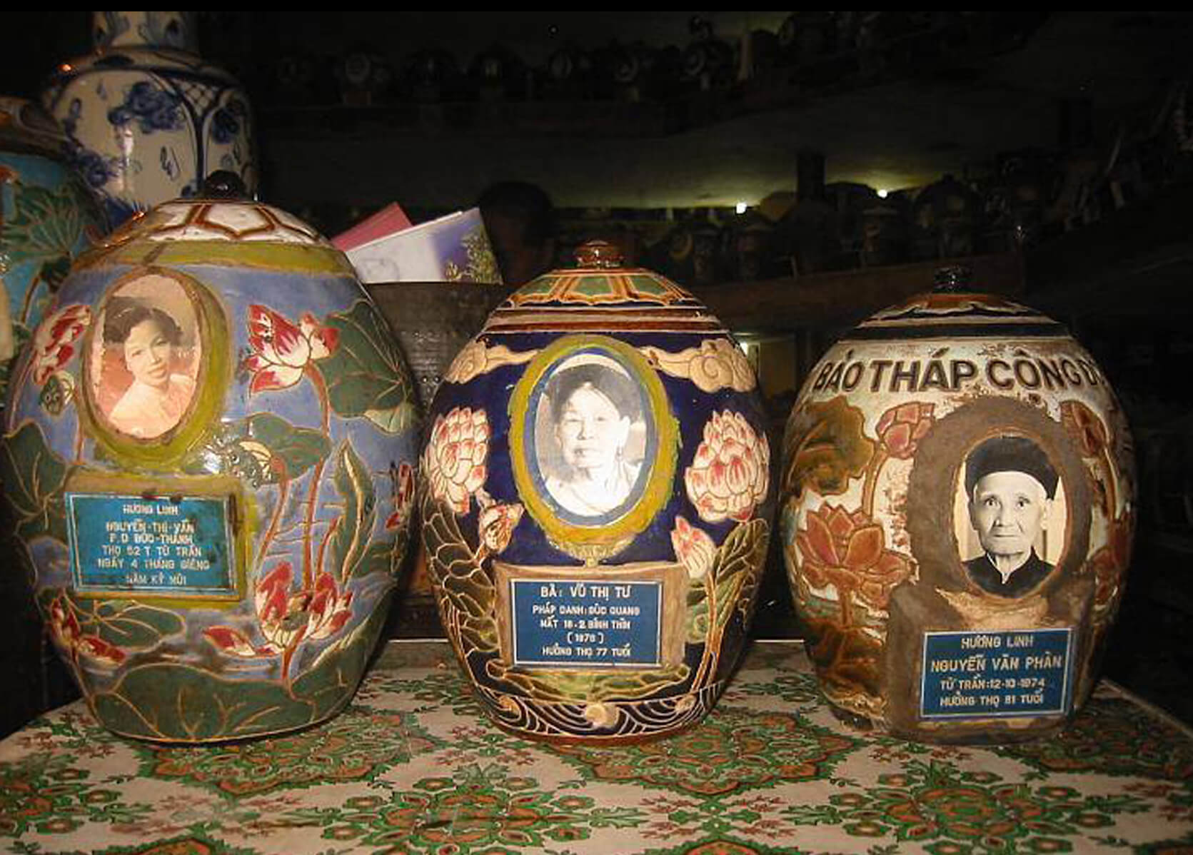 Three decorative Vietnamese pottery urns with photos of women on them.