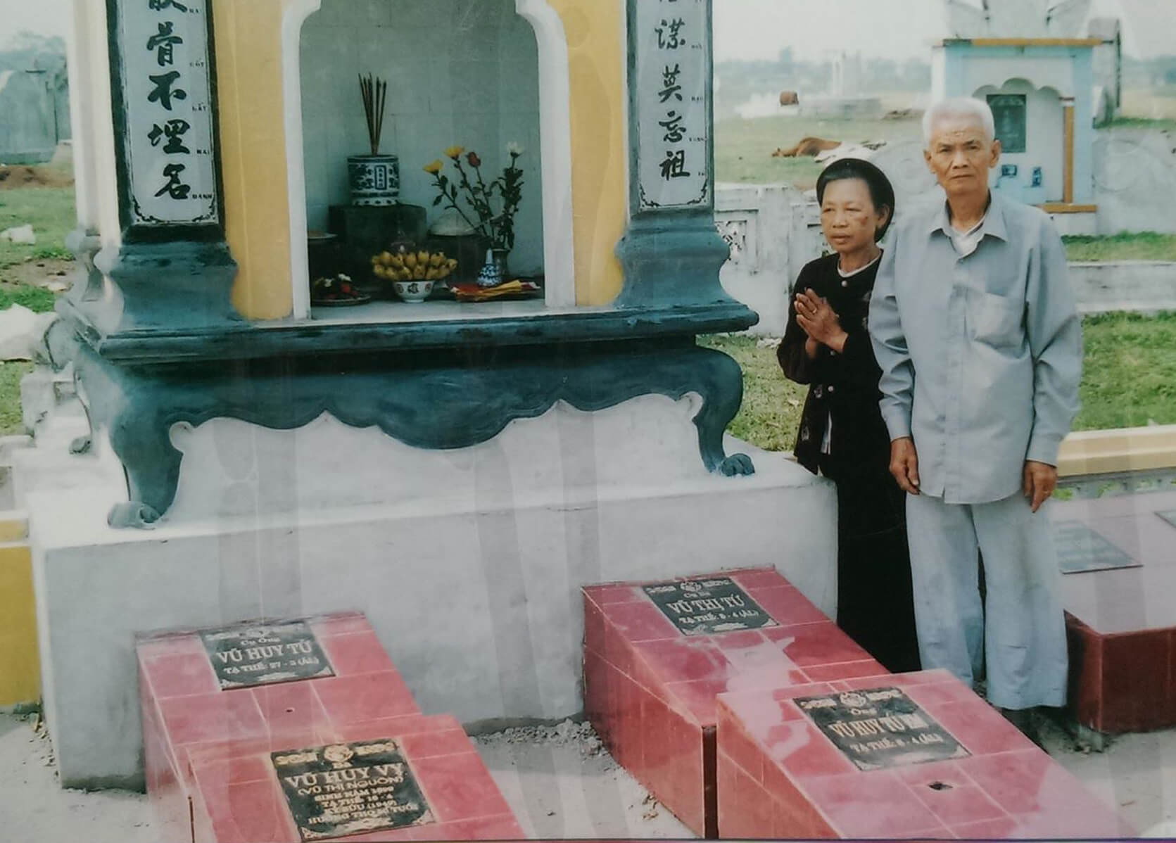 Vietnamese couple in front of an altar in a cemetery.