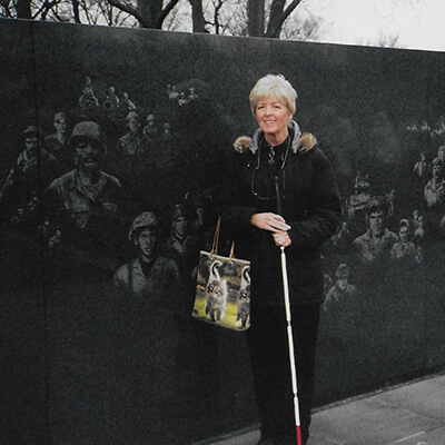An older woman with a cane posed next to the Vietnam Veterans Memorial.