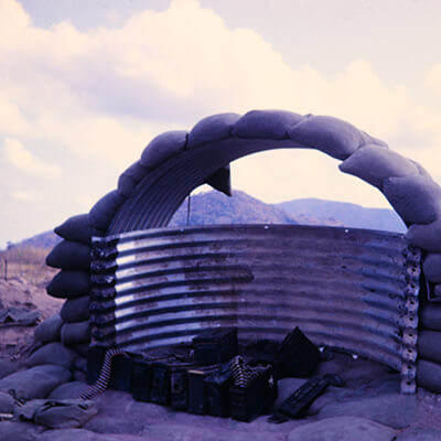 A guard's post with corrugated steel and sandbags, on top of a hill.