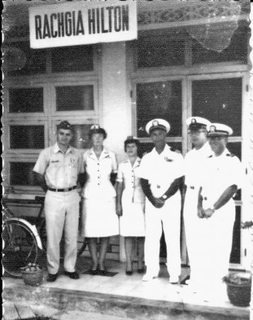 A group of 6 men and women posing outside a building marked "RACHGIA HILTON".
