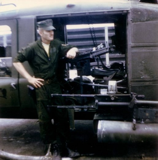 A soldier leaning up against a gun mounted to an aircraft.