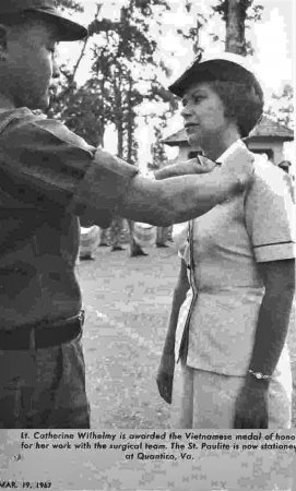 Newspaper photo of a young nurse in white Navy uniform getting a pin from an Asian soldier. Date on photo is March 19, 1967.