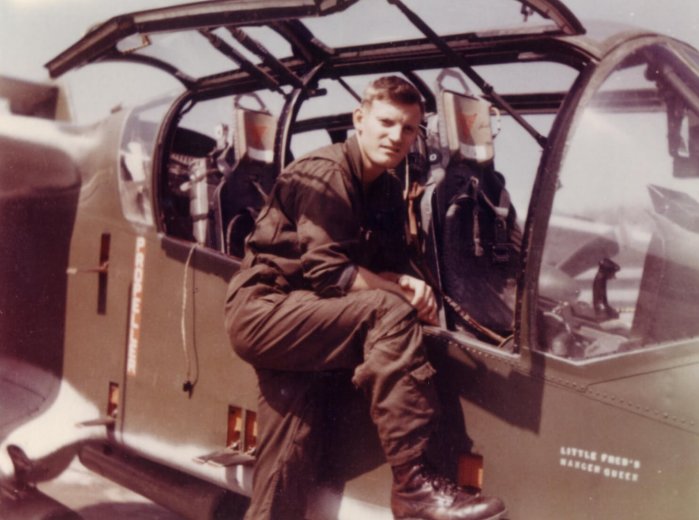 A young pilot posing next to the cockpit of an aircraft that says "Little Freds Hanger Queen" on it.