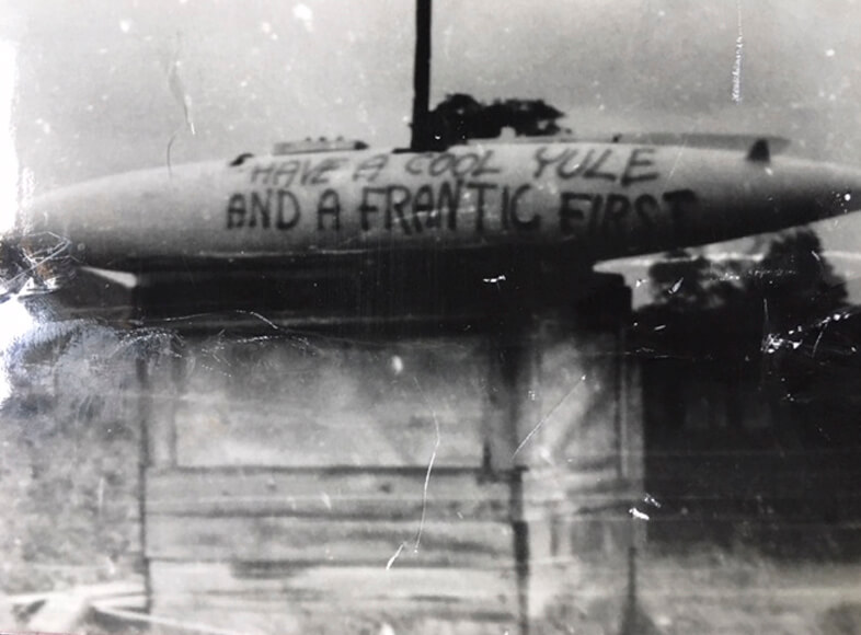 Black and white Vietnam War landscape photo of a camp and missile with text written on it.