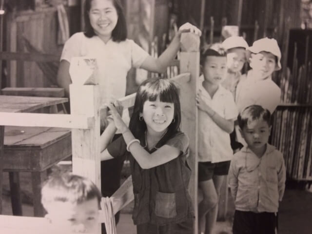 Black and white photo of a group of Vietnamese children and one young woman.