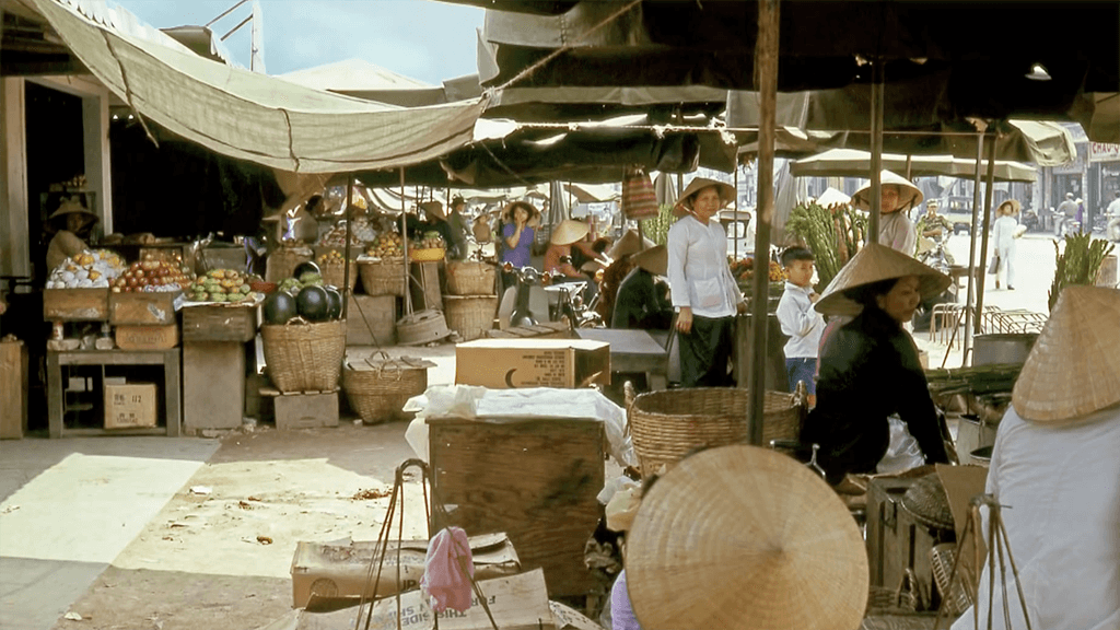 A Vietnamese marketplace, filled with produce, baskets, and women in conical straw hats.